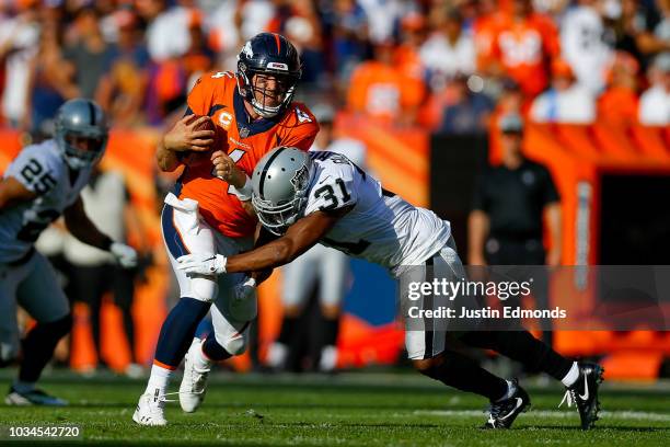 Quarterback Case Keenum of the Denver Broncos is hit by defensive back Marcus Gilchrist of the Oakland Raiders as he scrambles in the fourth quarter...