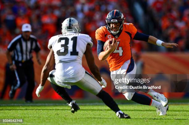 Quarterback Case Keenum of the Denver Broncos scrambles as defensive back Marcus Gilchrist of the Oakland Raiders defends in the fourth quarter of a...