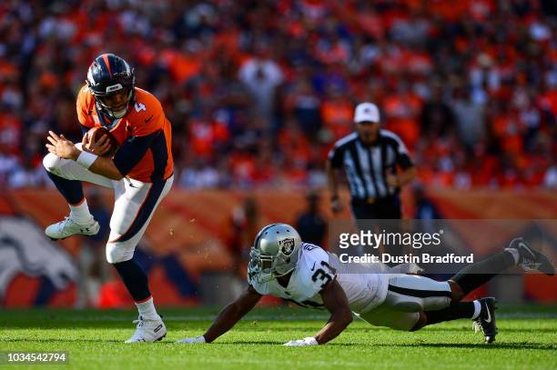 Quarterback Case Keenum of the Denver Broncos scrambles as defensive back Marcus Gilchrist of the Oakland Raiders defends in the fourth quarter of a...