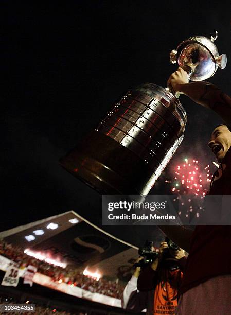 Alessandro of Internacional lift the trophy with fans after winning the match against Mexico's Chivas Guadalajara as part of Final 2010 Copa...