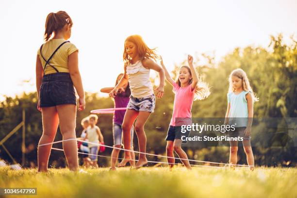 gruppe von kindern beim spielen im freien springen die ruber band - gummiband stock-fotos und bilder
