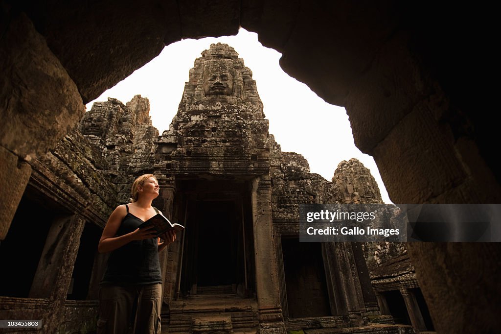 Female tourist exploring Bayon Temple using guide book, Angkor, Siem Reap Province, Cambodia