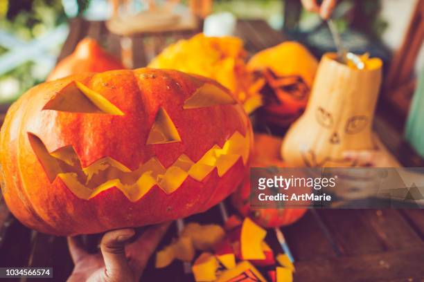 mann schnitzen gruselige gesicht auf einem kürbis in halloween - pumpkin stock-fotos und bilder