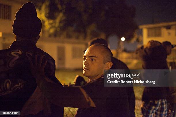 Police officers with the Los Angeles Police Department's gang unit search a group of men drinking in public outside the Jordan Downs Housing Project...