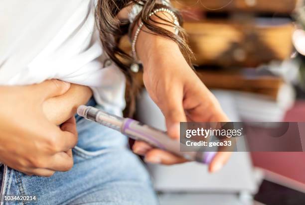 young woman injecting insulin in his abdomen - injecting stomach stock pictures, royalty-free photos & images