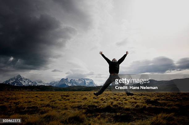 man jumping with arms and legs open in patagonia - arms open foto e immagini stock