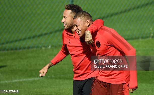 Paris Saint-Germain's Brazilian forward Neymar jokes with Paris Saint-Germain's French forward Kylian MBappe during a training session at the Camp...