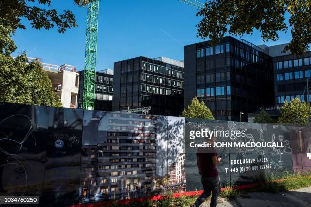 Man walks past a construction site advertising residential units near the so-called East Side Gallery, a 1,3 km-long stretch of the Berlin wall, on...