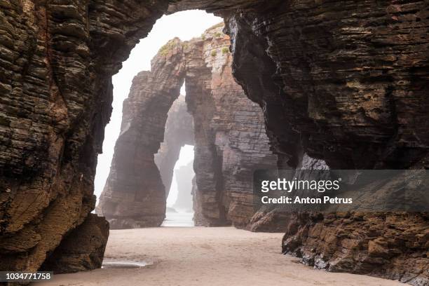 natural rock arches on cathedrals beach in low tide, spain - cliff shore stock-fotos und bilder