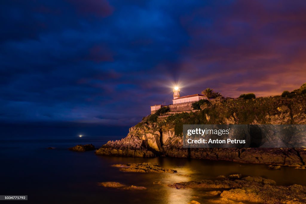 Dramatic night landscape with lighthouse, Cudillero, Spain