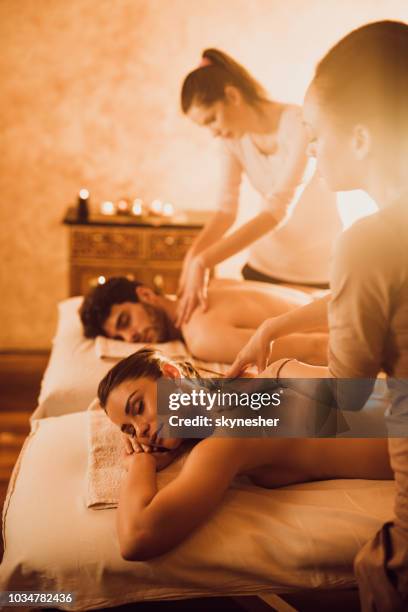 female therapists massaging young couple at the spa. - massage couple stock pictures, royalty-free photos & images