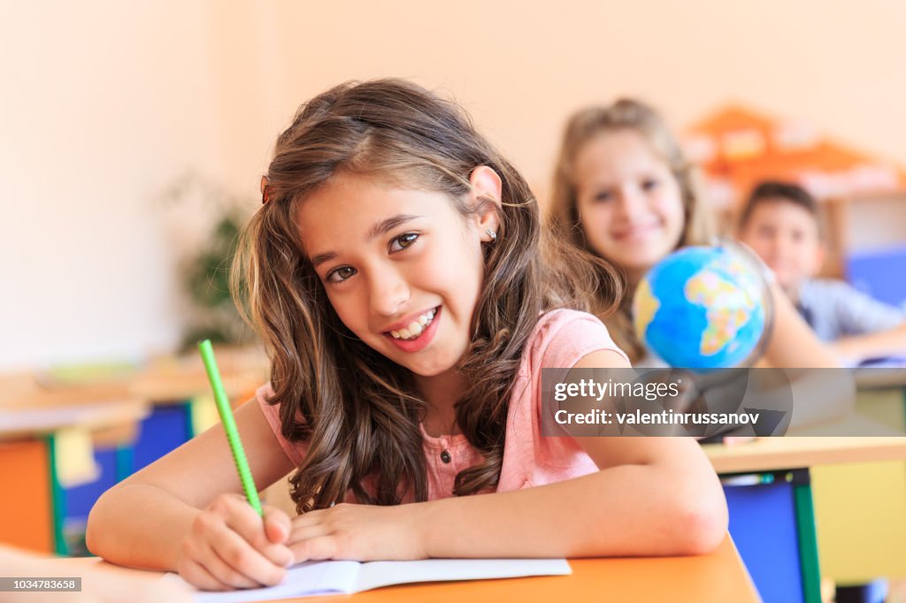 Smiling schoolgirl drawing in classroom