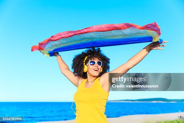 african woman in yellow outfit listen music on the beach - beach music stock pictures, royalty-free photos & images