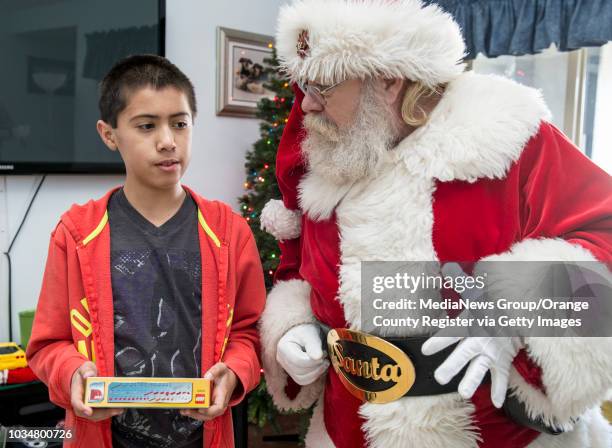 Carlos Belles left, listens as Santa Claus talks about the gift he gave the boy. The Santa visit and gifts was sponsored by the Huntington Beach...