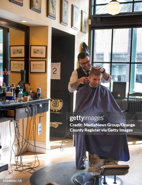 Barber Gabe Luevano, left, of Barbeer Cut and Beer, cuts the hair of client Edgar Mendoza of Buena Park. Barbeer is one of the businesses in the...