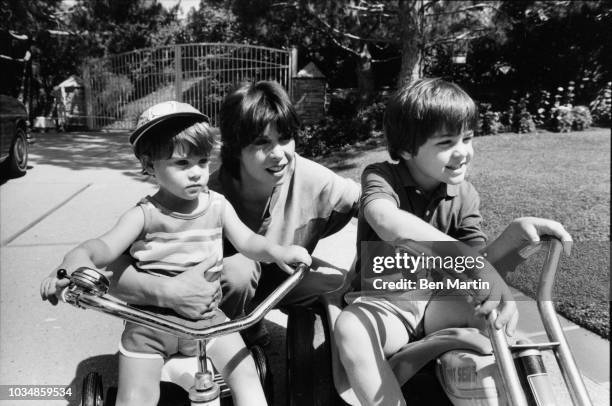 Talia Shire with her sons Matthew Shire and Jason Schwartzman riding bikes in the garden of their Belair home, July 22, 1982.