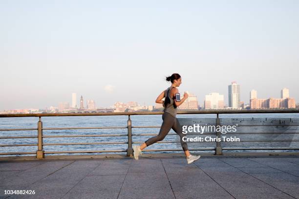 young woman running along hudson river - forward athlete stock pictures, royalty-free photos & images