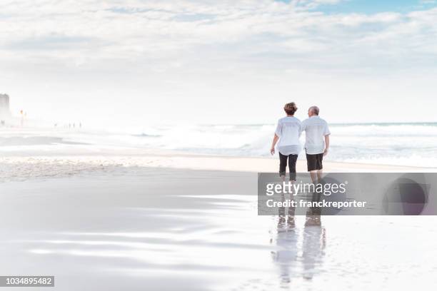 happiness senior couple walking togetherness on the beach - queensland beaches stock pictures, royalty-free photos & images