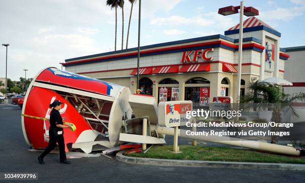 Employees put up caution tape around a downed sign after strong winds toppled the giant chicken bucket sign at the KFC in the 4500 block of Atlantic...