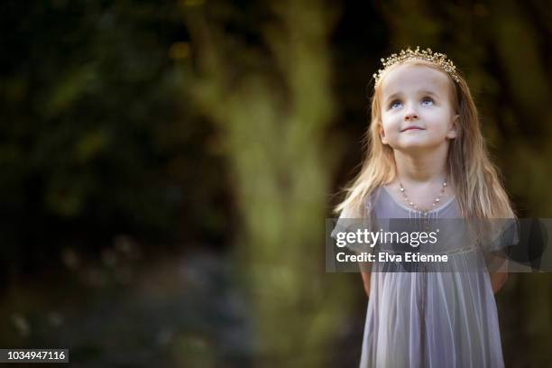 smiling girl, daydreaming in back yard, wearing pretty dress, jewellery and tiara - kids tiara stock pictures, royalty-free photos & images