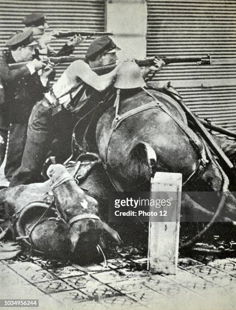 Three republican fighters take aim with rifles, behind a barricade made up of dead horses. Barcelona 1937, during the Spanish civil war 1938.