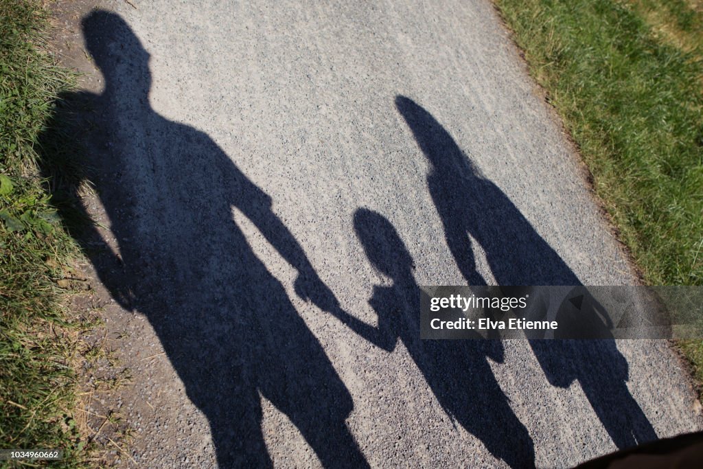 Shadow on gravel path of a family of three, holding hands