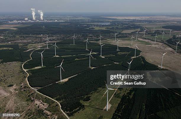 Wind turbines spin to produce electricity as steam rises from cooling towers at the Jaenschwalde coal-burning power plant behind on August 20, 2010...