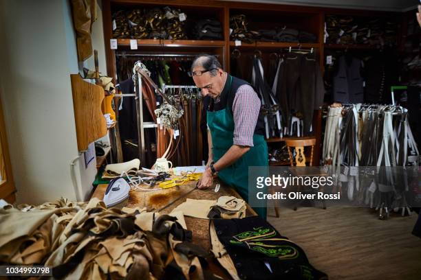 tailor working on samples for bavarian lederhosen - sastre fotografías e imágenes de stock