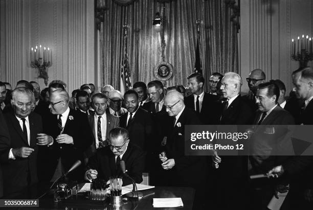 Photograph of Lyndon Johnson, President of the United States of America, signing Civil Rights Act. Behind Johnson is Martin Luther King Jnr Dated...