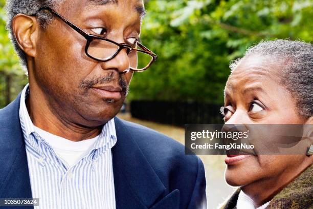 close up of senior african couple looking at each other outdoors - raised eyebrows imagens e fotografias de stock