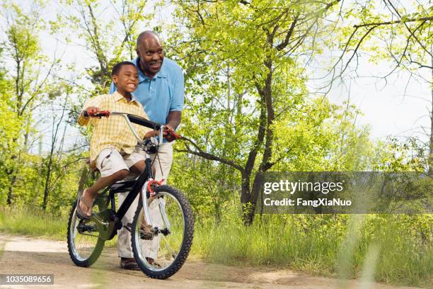 afrikanische großvater lehre enkel radfahren im park - fahrrad fahren großeltern mit kind stock-fotos und bilder