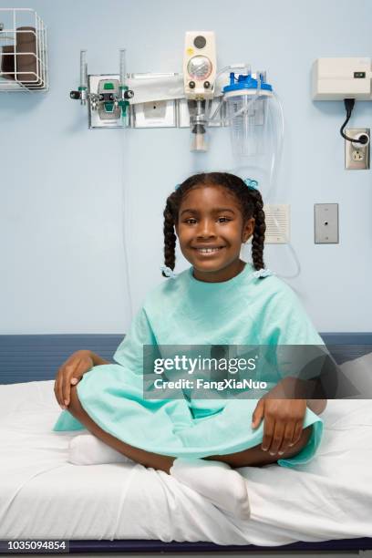 young african girl sitting in hospital bed smiling - hospital gown imagens e fotografias de stock