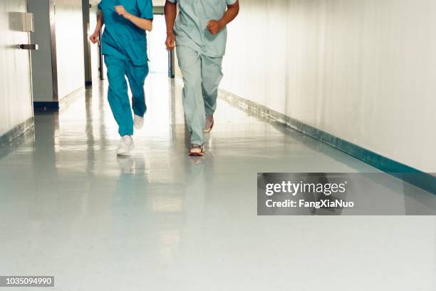 two nurses running down corridor in hospital - hospital corridor stock pictures, royalty-free photos & images