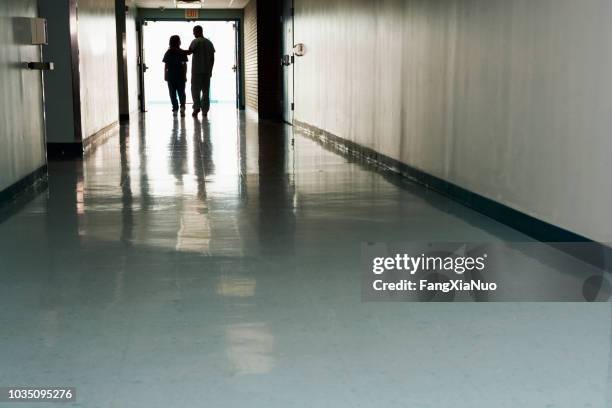 two people standing at end of corridor in hospital - mourning imagens e fotografias de stock