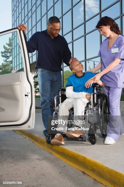 african boy in wheelchair leaving hospital with father - leaving hospital stock pictures, royalty-free photos & images