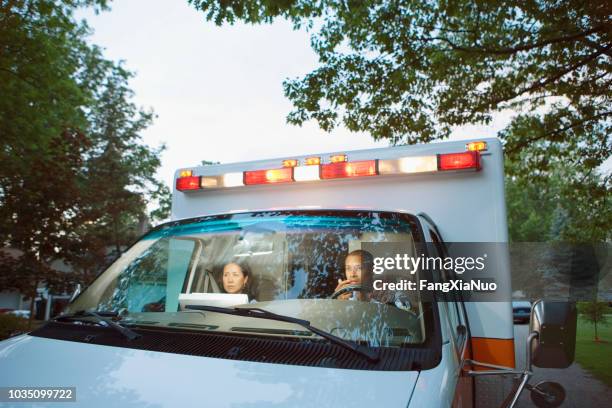 male and female paramedics in cab of ambulance - paramedic stock pictures, royalty-free photos & images