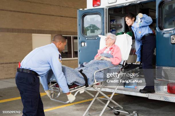 paramedics putting senior woman into ambulance - ambulance arrival stock pictures, royalty-free photos & images