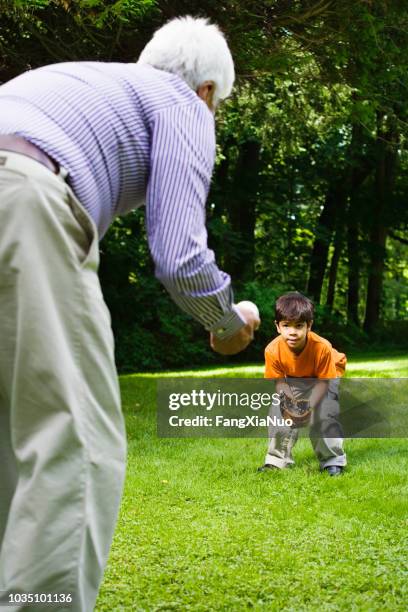 hispanic boy playing catch with grandfather in park - grandpa playing catch stock pictures, royalty-free photos & images