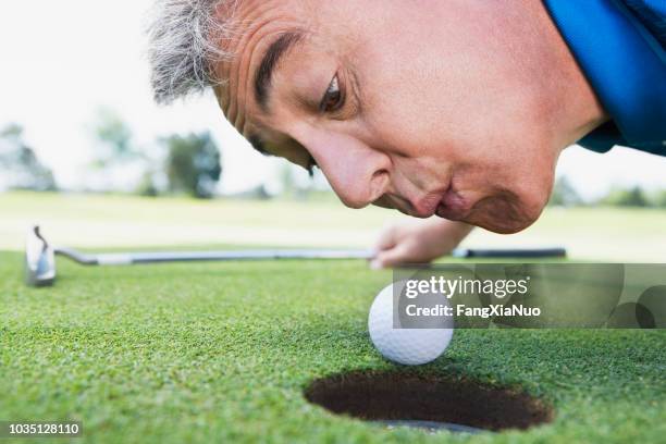 uomo che soffia sulla pallina da golf - golf cheating foto e immagini stock
