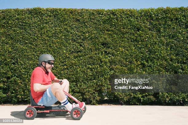 hispanic man riding child's toy - go carting stock pictures, royalty-free photos & images