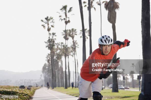 asian man rollerblading - inline skating man park stock pictures, royalty-free photos & images