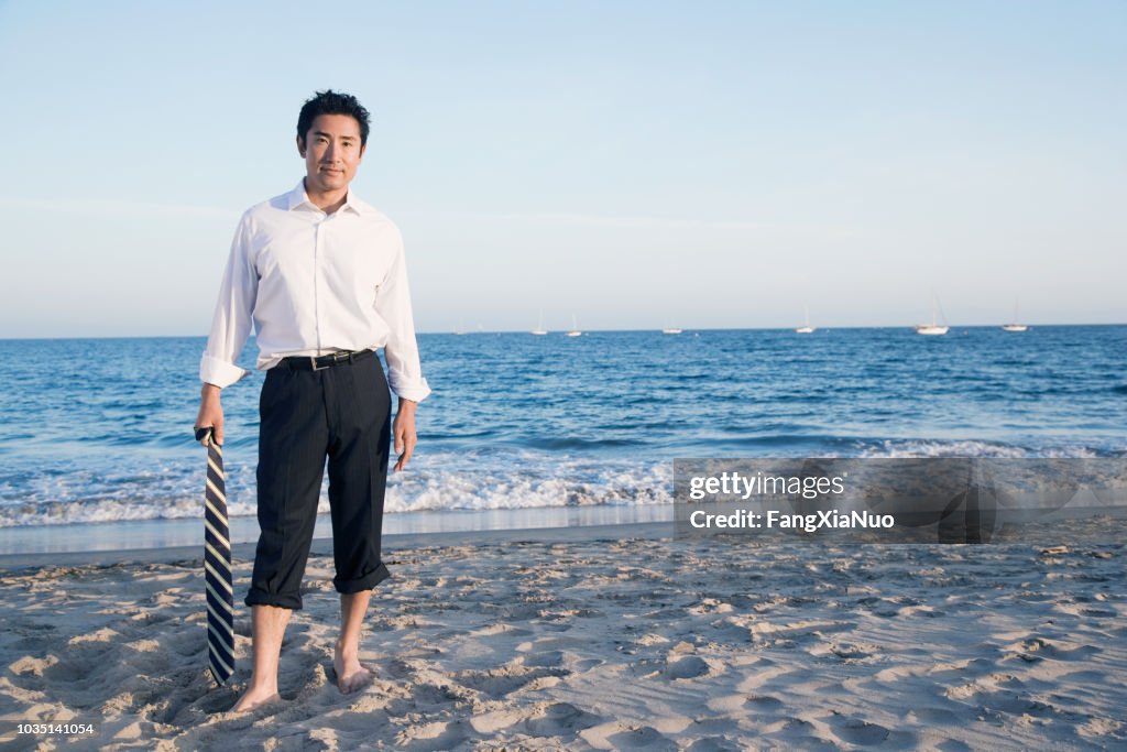 Homem de negócios asiático em pé na praia