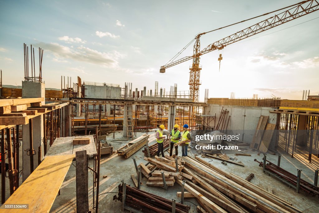 Cantiere con tre ingegneri e gru in cima al nuovo grattacielo