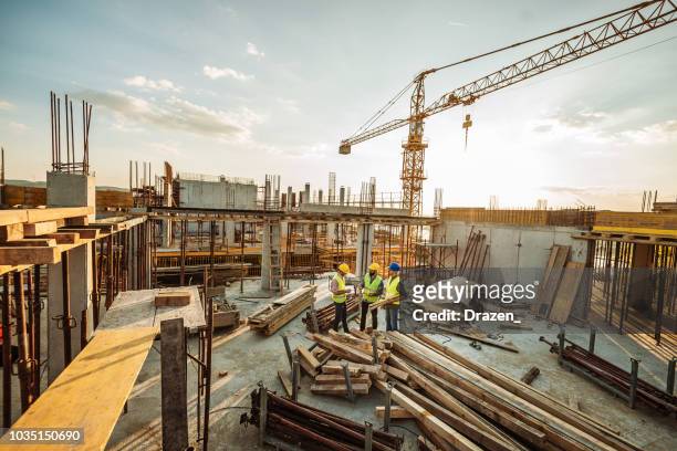 construction site with three engineers and crane on the top of new skyscraper - obras imagens e fotografias de stock