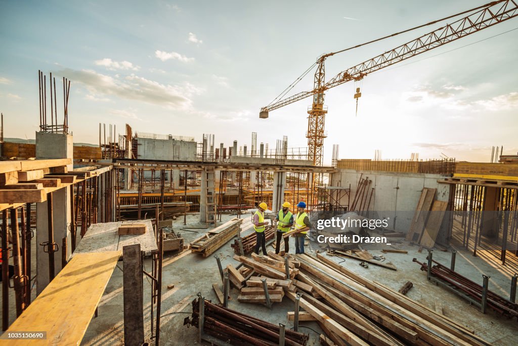 新建摩天大樓頂部有三名工程師和起重機的施工現場