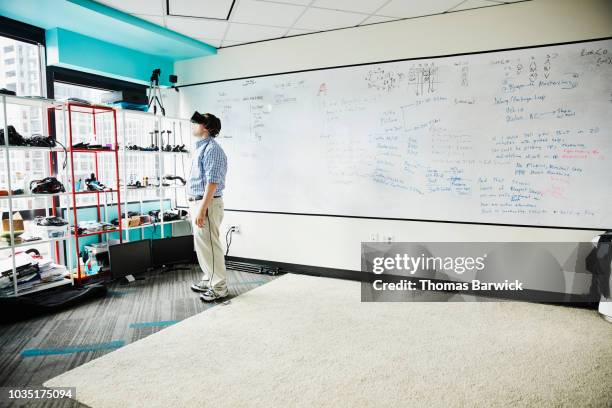 engineer wearing virtual reality headset while testing program in virtual reality lab - simulation lab stock pictures, royalty-free photos & images