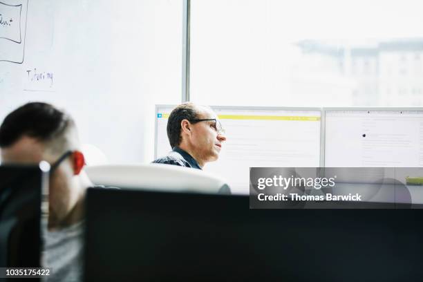 engineer in discussion with coworker while working in computer lab - older software developer stock pictures, royalty-free photos & images