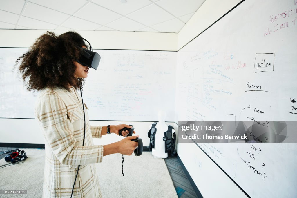 Female engineer testing program on virtual reality headset in computer lab