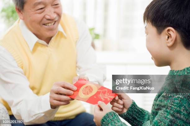 chinese grandfather giving grandson red pocket - chinese new year red envelope stock pictures, royalty-free photos & images
