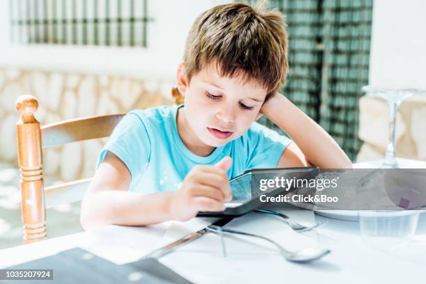 five years old boy with tablet sitting on a chair and leaning on a table (outdoors) - children restaurant stockfoto's en -beelden